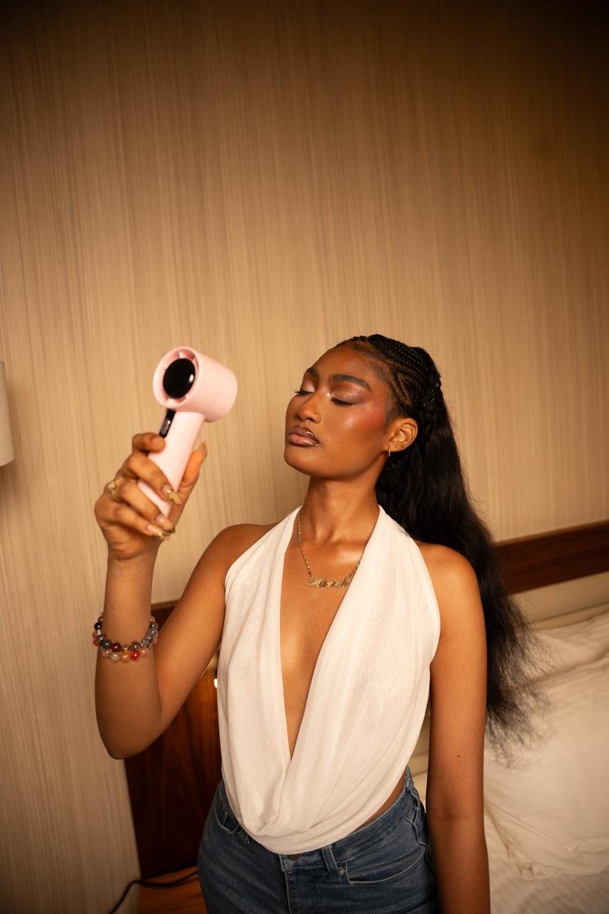 ALMA handheld fan in blush pink held up in an editorial portrait