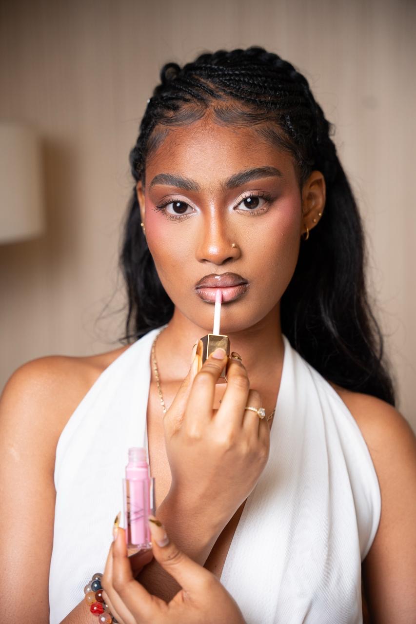 Model applying ALMA lip gloss with the pink shade in hand
